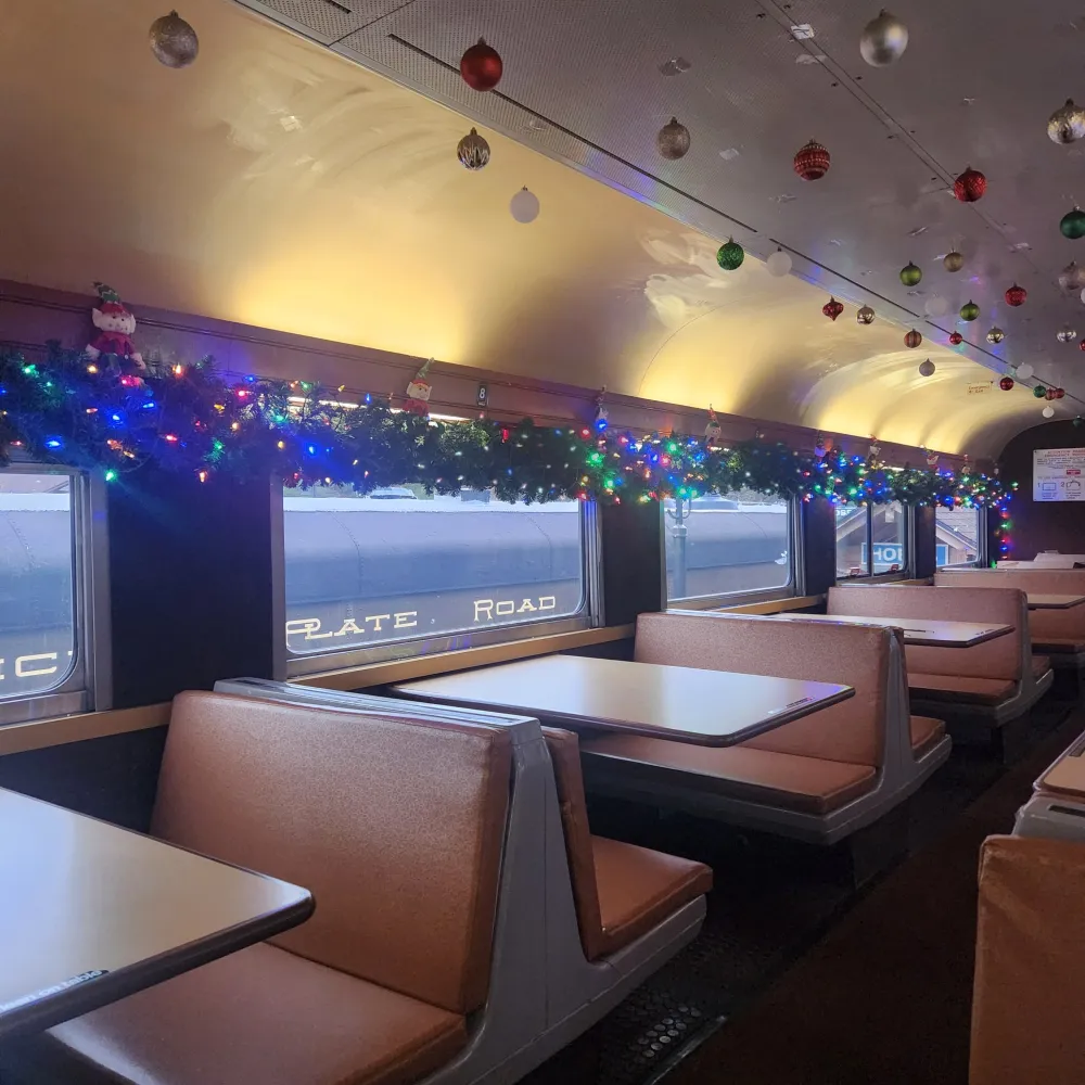 Booths and tables on a train car decorated for Christmas