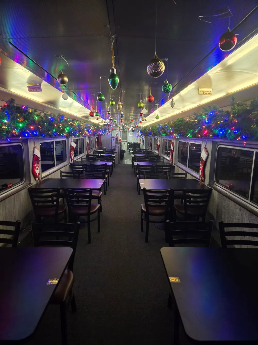Black tables and chairs on a train car decorated for Christmas