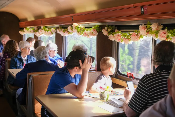 People sitting in a train with flower decorations, looking out the window at scenery.