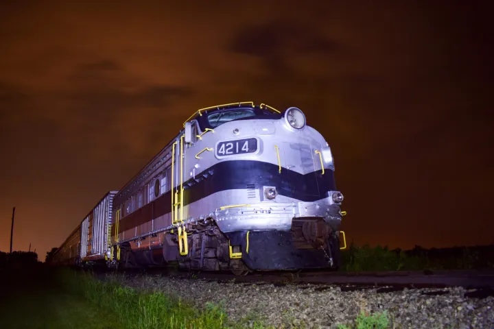 Vintage train with number 4214 on the side, under a cloudy night sky with a reddish hue.