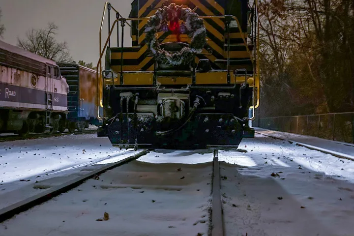 Train at night decorated with a wreath on snowy tracks.