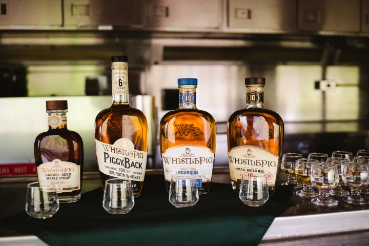 Four bottles of whiskey with tasting glasses on a table.