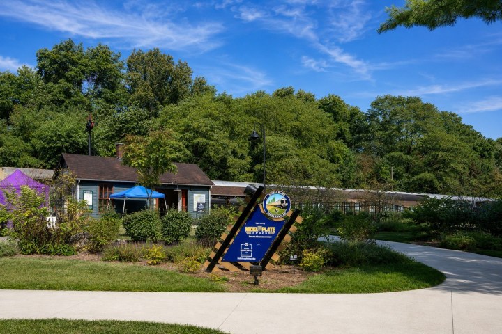 A small building with a blue sign in a park setting under a clear sky.