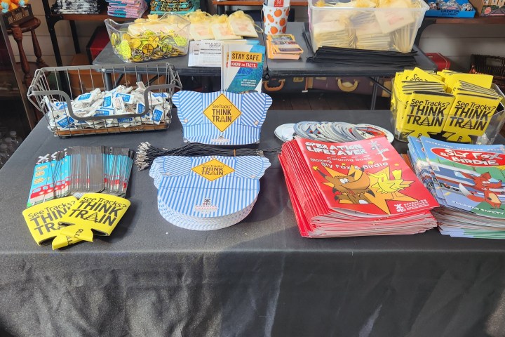Table with train-themed merchandise and safety pamphlets in a store.